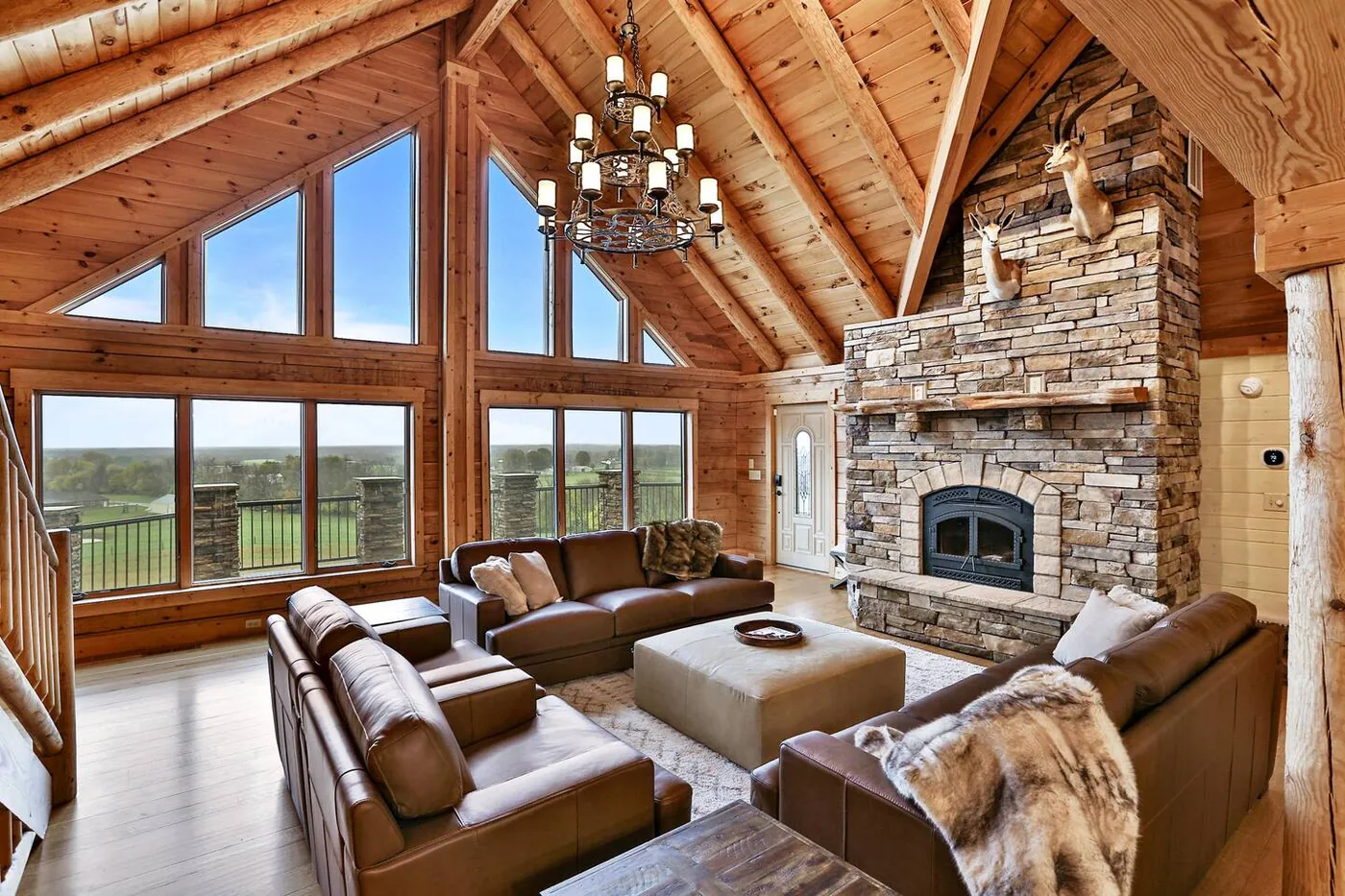 Great room with vaulted log ceiling, stone fireplace and floor-to-ceiling windows